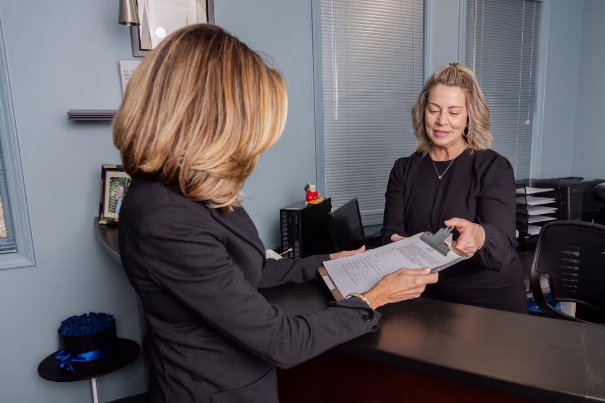 Receptionist handing clipboard to patient at front desk